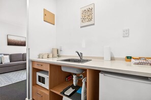 A modern kitchenette with a built-in microwave, sink, and storage cabinets. - Inviting 1BR Escape in Auckland CBD Zodiak Stays (Auckland)