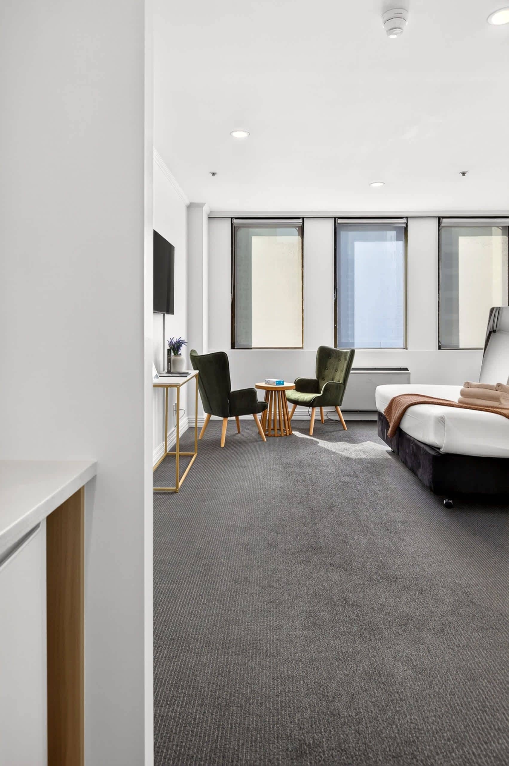 Habitación de hotel moderna con cama, dos sillas, una mesita y un televisor.