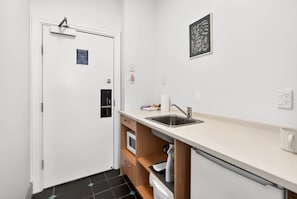 A compact kitchen with a built-in oven, a sink, and a microwave. - Your Central Auckland City Escape Zodiak Stays (Auckland)