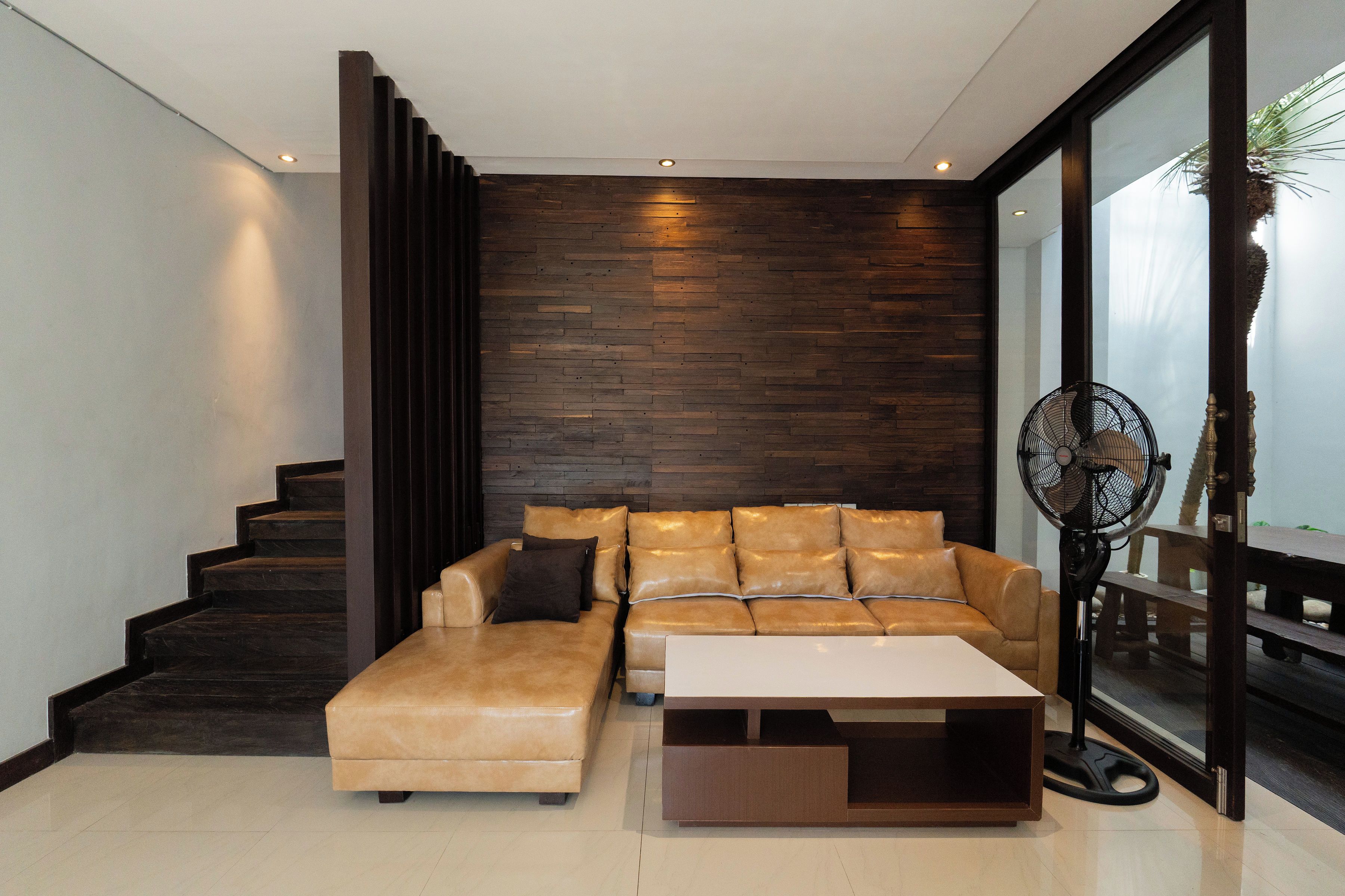 A modern living room with a sofa, a coffee table, and a fan.