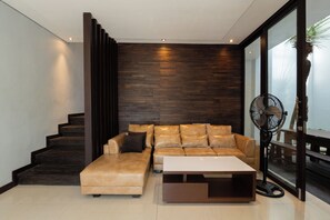 Una sala de estar moderna con un sofá, una mesa de centro y un ventilador.