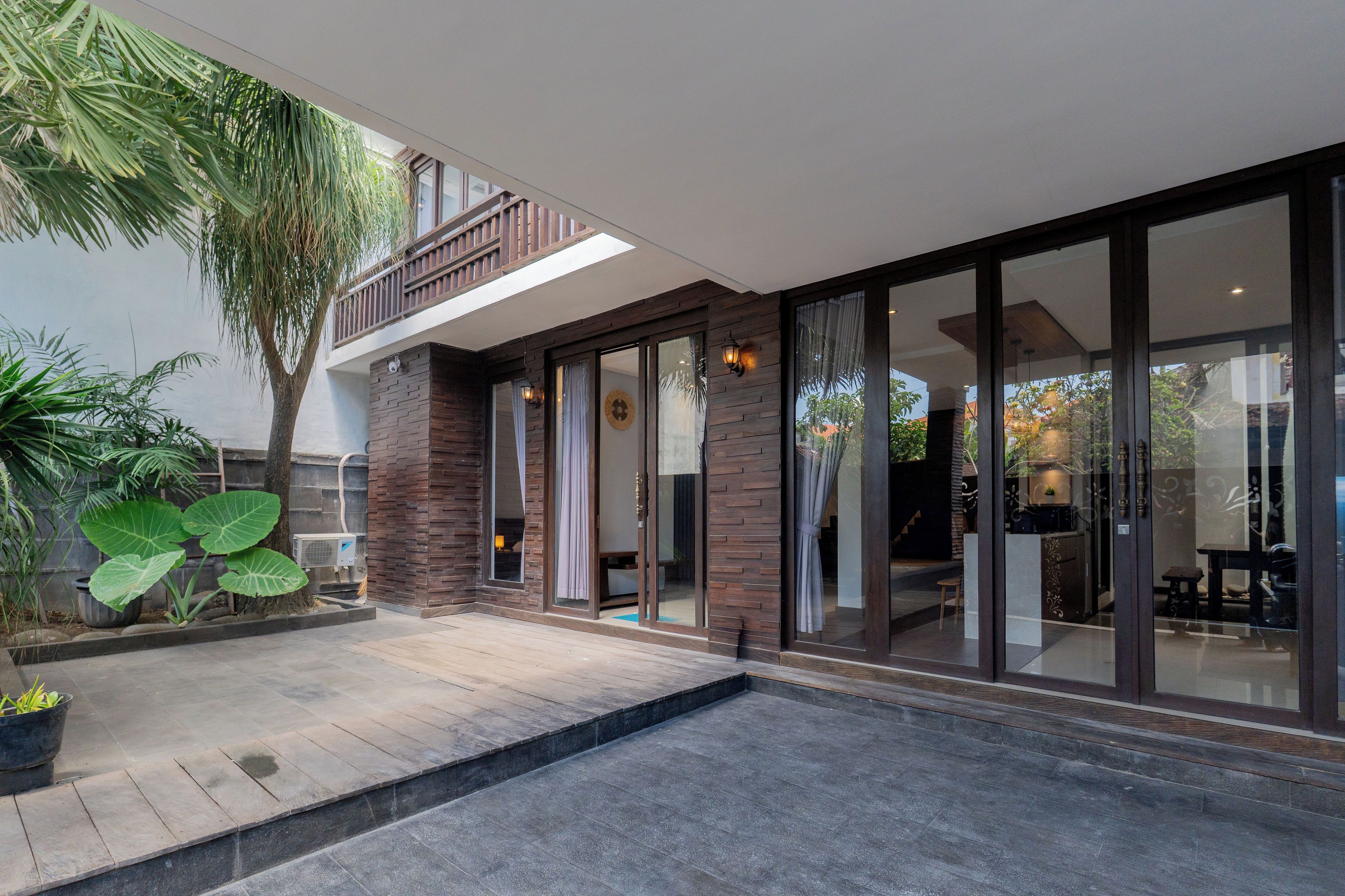 A modern house with a patio, large windows, and a view of the surrounding area.