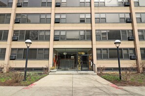 A multi-story building with a beige facade, numbered 1606, featuring a glass entrance and air conditioning units.