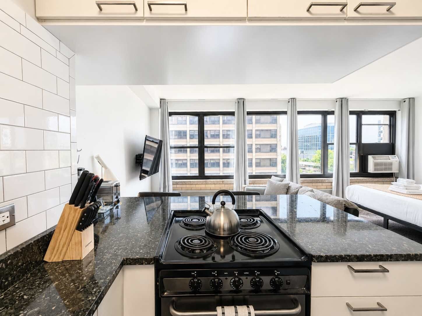 A modern kitchen with a stove, a kettle, and a knife block.