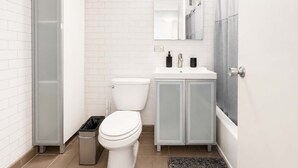 Un baño moderno con inodoro, lavabo y zona de ducha.