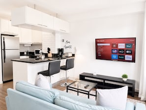 A modern kitchen with white cabinets, a black countertop, and a coffee machine.