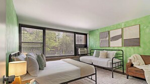 Une chambre à coucher avec un lit, une table de chevet, une lampe et une fenêtre avec des stores.