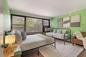 Un dormitorio con cama, mesita de noche, lámpara y ventana con persianas.
