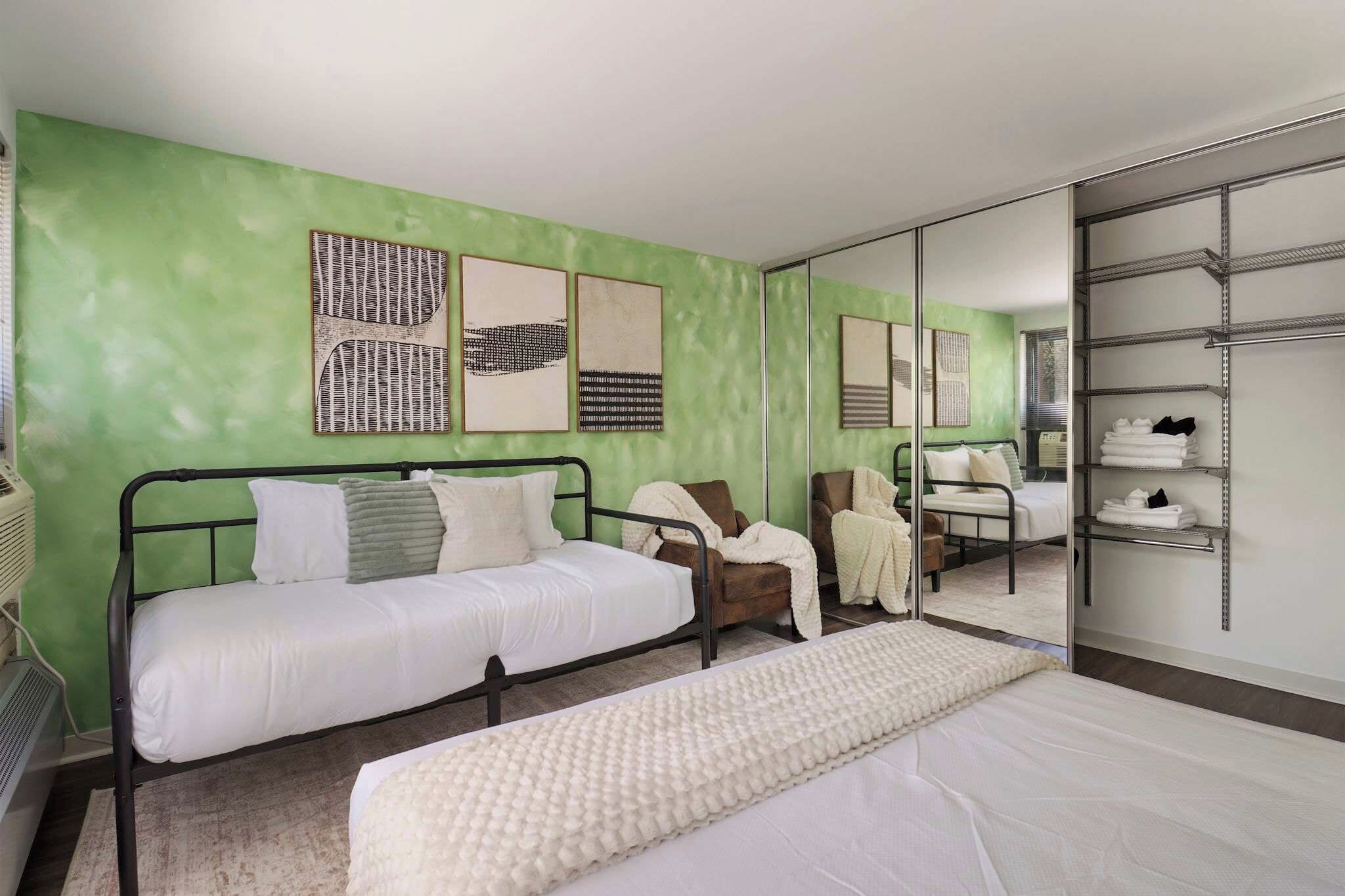 Ein Hotelzimmer mit Bett, Stuhl, Spiegel und Kleiderschrank.