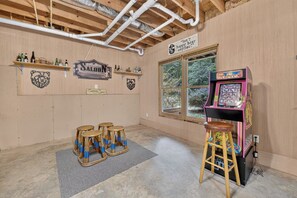 A room with wooden walls, a Pac-Man arcade machine, and a sign that says 'Isn't happy hour?' - Family Getaway Hot Tub, Fire Pit, Game Room, Pool, Gym, near apple orchards (Ellijay)