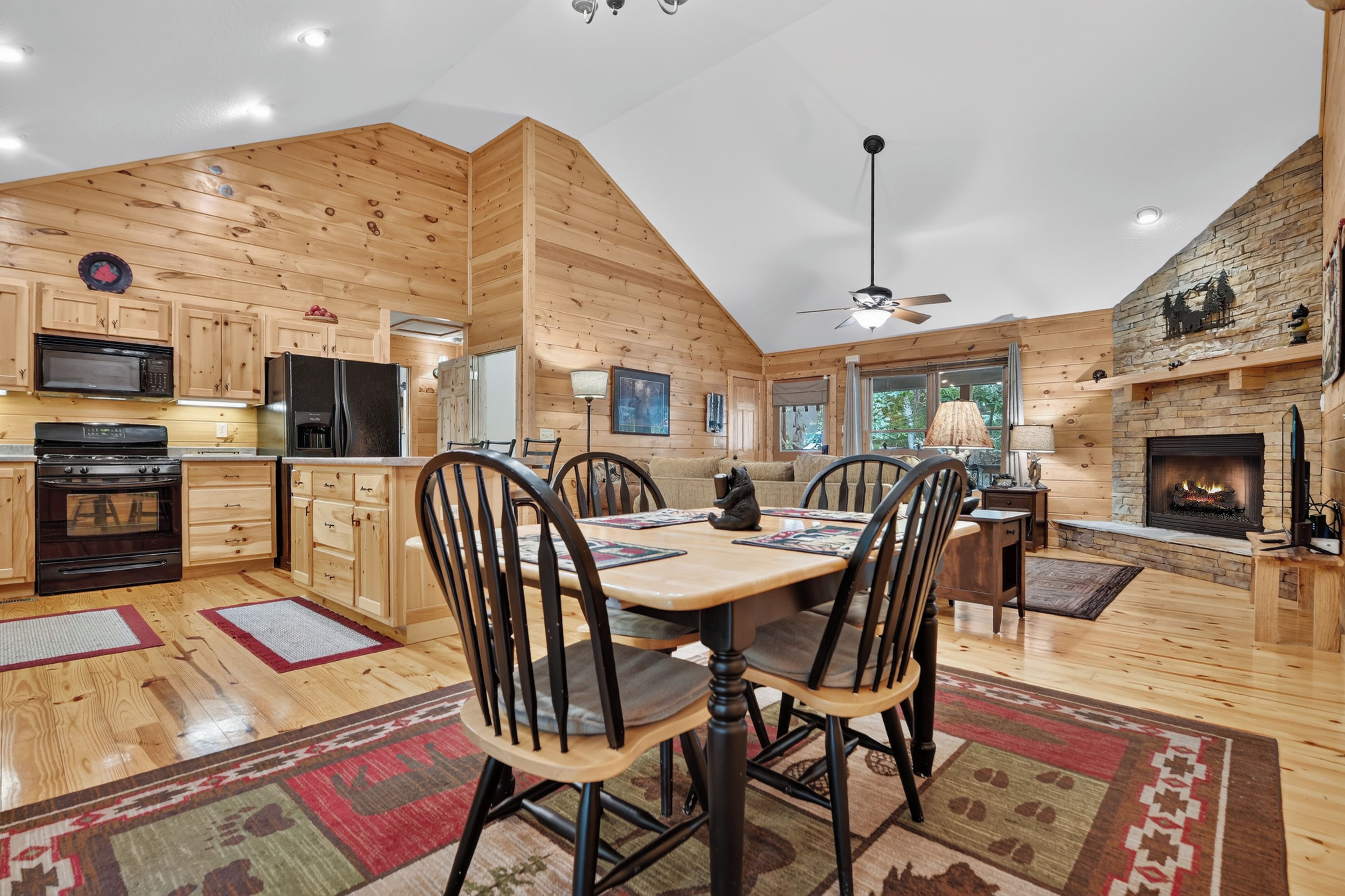 Intérieur moderne d’une cabane en rondins, comprenant un coin repas, une cuisine et une cheminée.