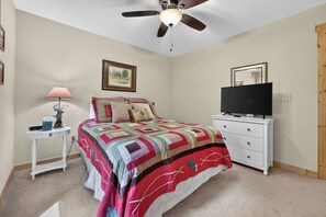 A bedroom with a bed, a television on a dresser, a ceiling fan, a lamp, and a framed picture on the wall. - Family Getaway Hot Tub, Fire Pit, Game Room, Pool, Gym, near apple orchards (Ellijay)