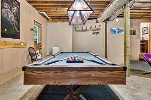 A pool table with a wooden frame, a pool cue, and balls, in a room with wooden walls and a ceiling with exposed beams. - Family Getaway Hot Tub, Fire Pit, Game Room, Pool, Gym, near apple orchards (Ellijay)