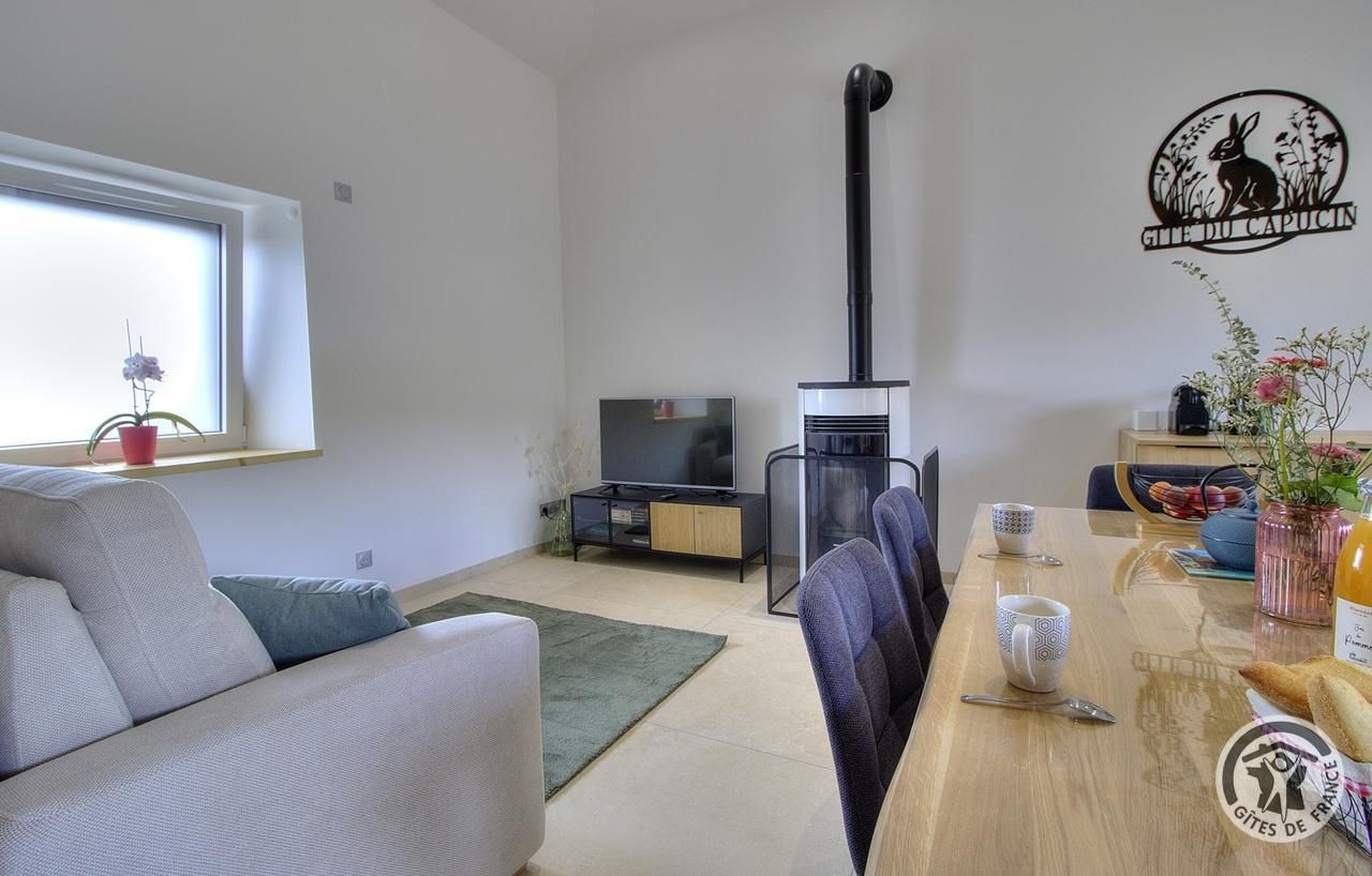 Moderni olohuone, jossa on sohva, ruokapöytä tuoleineen, televisio ja takka.