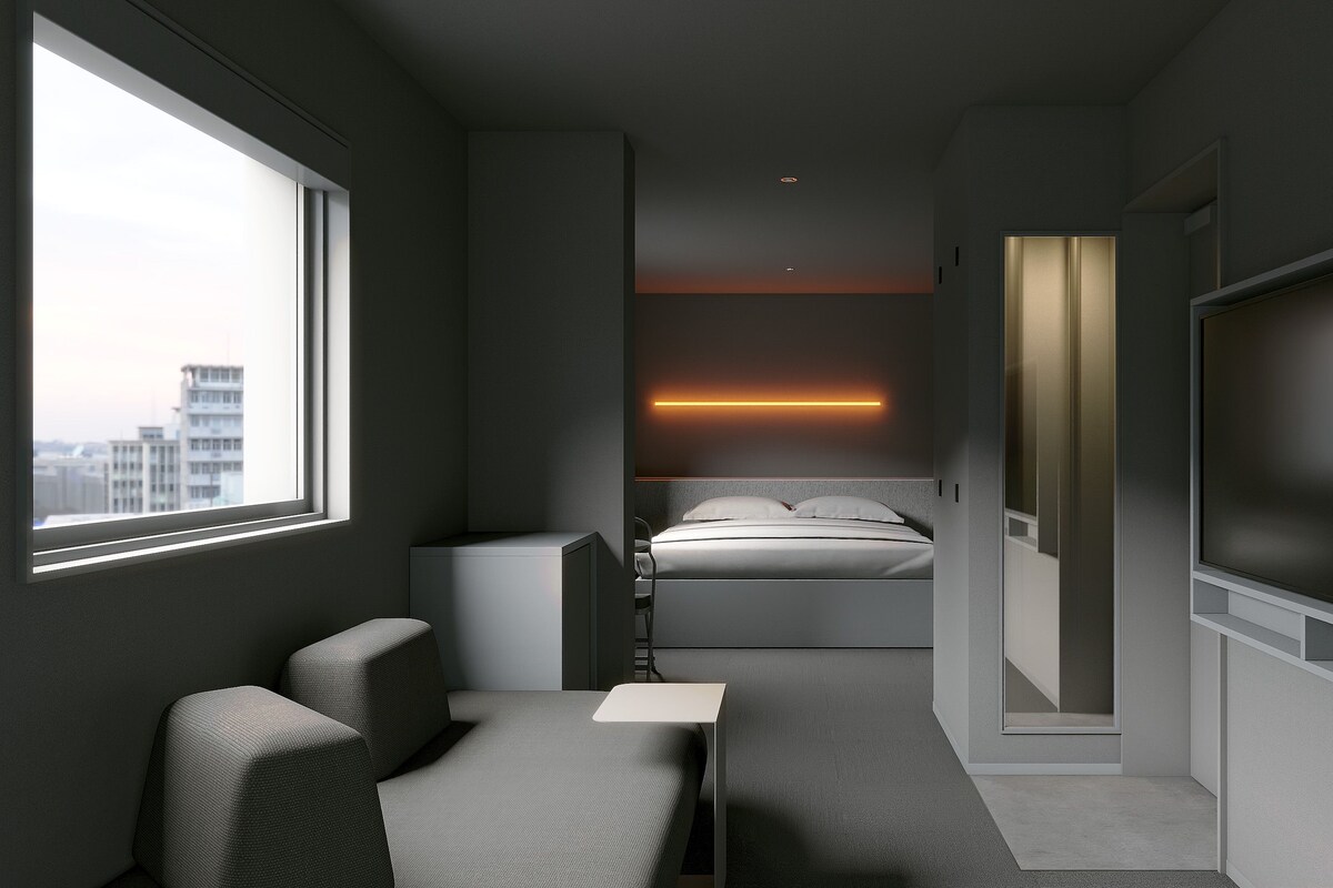 A modern hotel room with a bed, a desk, a chair, a TV, and a large window.