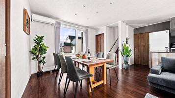 A modern living room with a dining area, wooden flooring, and a staircase leading to an upper level.