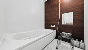 A modern bathroom with a freestanding bathtub, a glass shower enclosure, and a built-in mirror. - The Cross (Asahikawa)
