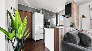 Un espace de vie compact comprenant un coin cuisine, un canapé et une plante en pot.