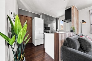 Un espacio habitable funcional con kitchenette, sofá y una planta en maceta.