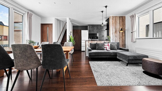 A modern living space with a dining area, a sofa set, and a kitchen in the background. - The Cross (Asahikawa)