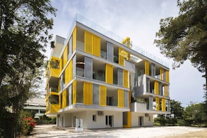 A multi-story building with balconies, large windows, and a flat roof. - Holiday flat with air conditioning (Bibione)