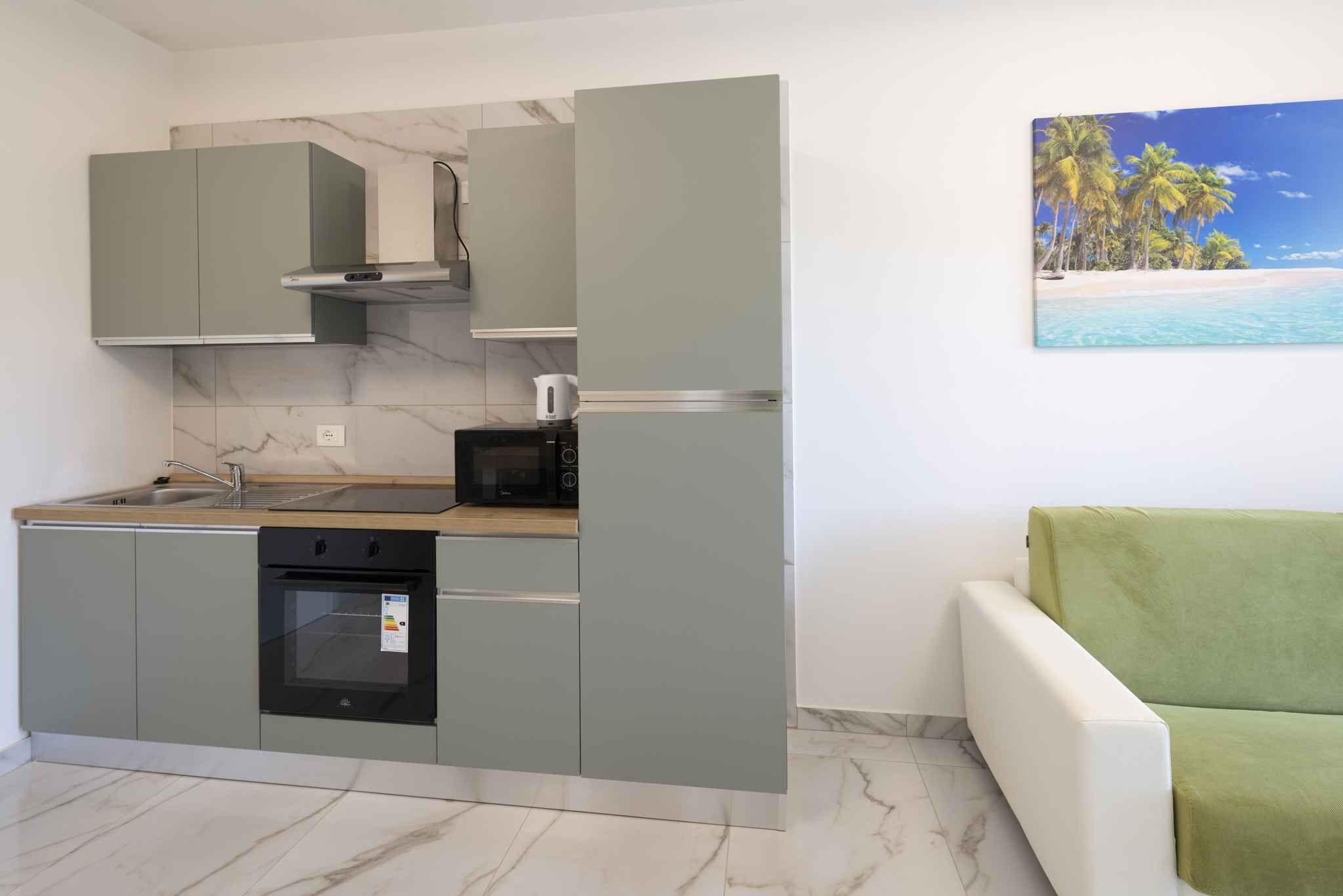 Cocina compacta con horno integrado, microondas y una pequeña encimera.