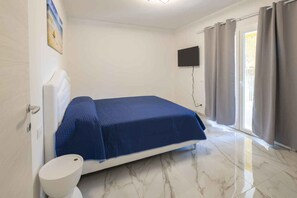 A bedroom with a bed, a toilet, a TV, and a window with curtains. - Holiday flat with air conditioning (Bibione)