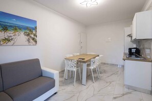 Ett kompakt bostadsutrymme med en matplats, ett litet kök och en soffa.