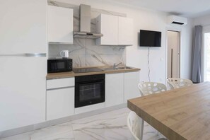 A modern kitchen with white cabinets, a microwave, an oven, and a wooden countertop. - Holiday apartment with air conditioning (Bibione)