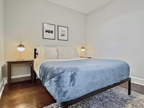 Une chambre à coucher comprenant un lit, deux tables de chevet et deux lampes fixées au mur.