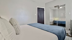 Une chambre à coucher avec un lit, un ventilateur de plafond, une porte et un miroir.