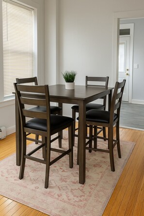 A dining area with a rectangular table, four chairs, and a potted plant. - 1BR Unit w/ 2 Comfy Beds (Chicago)