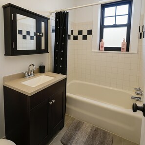 A bathroom with a bathtub, a sink, a mirror, and a window with a view. - 1BR Unit w/ 2 Comfy Beds (Chicago)