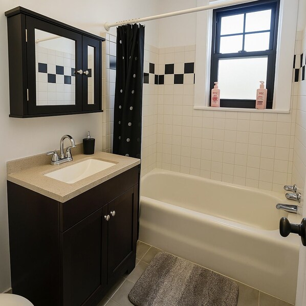 A bathroom with a bathtub, a sink, a mirror, and a window with a view.