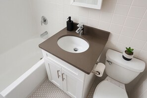 A bathroom with a bathtub, a sink, and a toilet. - Hyde Park Trendy Studio Apartment in Good Spot (Chicago)