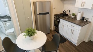 A modern kitchen with a stainless steel refrigerator, a stove, and white cabinets. - Hyde Park Trendy Studio Apartment in Good Spot (Chicago)