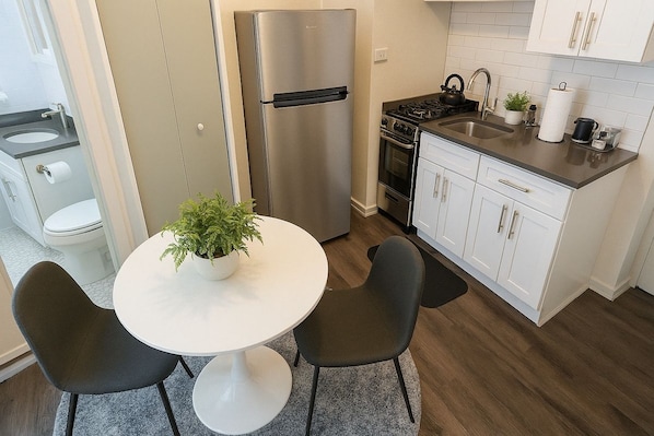 A modern kitchen with a stainless steel refrigerator, a stove, and white cabinets.