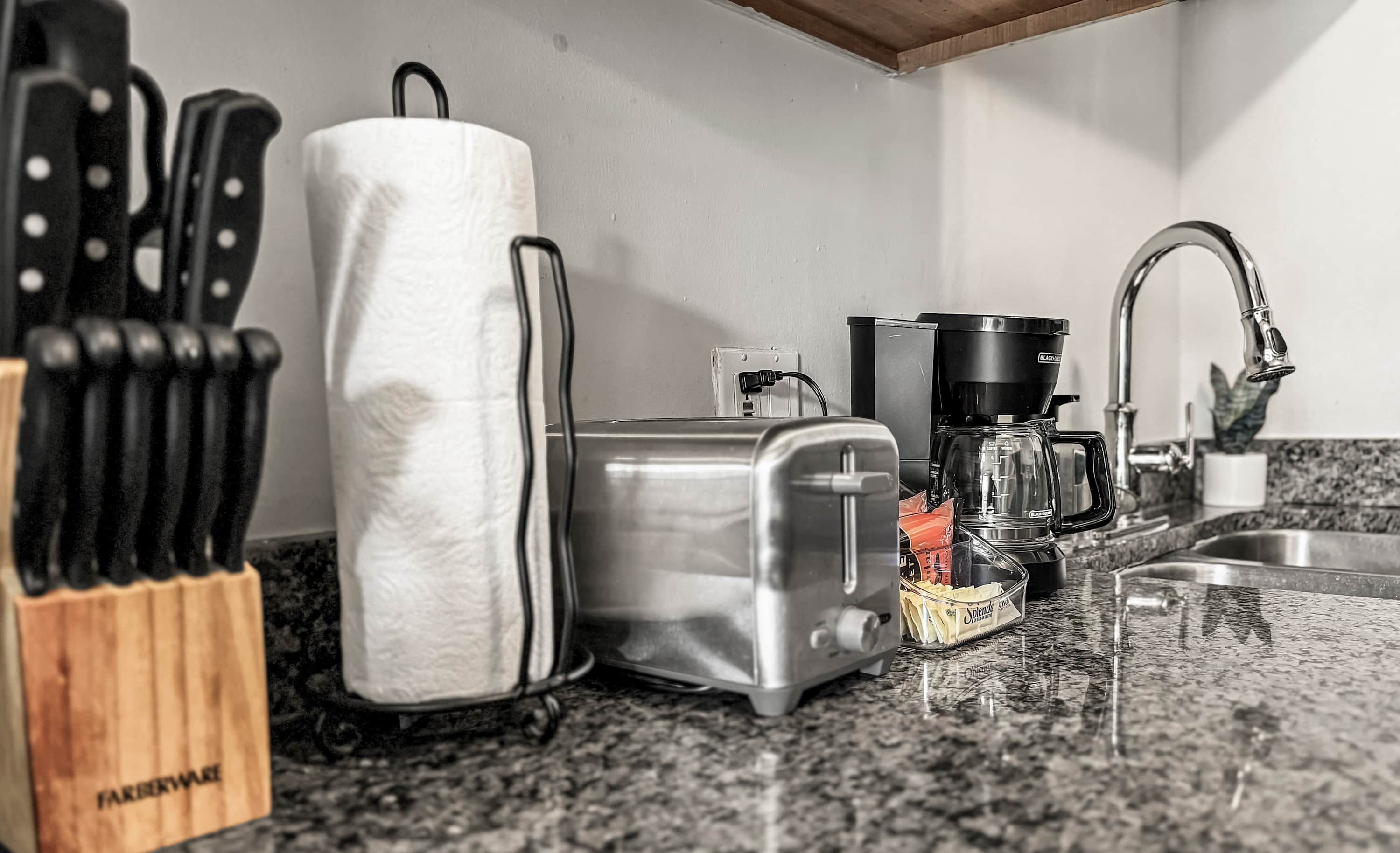 Una cocina con tostadora, cafetera y bloque de cuchillos.
