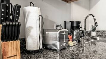 Una cocina con tostadora, cafetera y bloque de cuchillos.