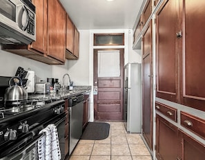 A compact kitchen with wooden cabinets, a stove, a refrigerator, and a microwave.