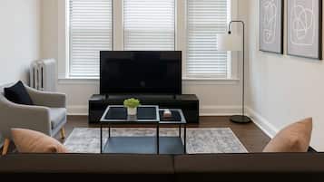 A modern living room with a flat-screen TV, a sofa, a coffee table, and a radiator.