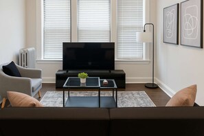 A modern living room with a flat-screen TV, a sofa, a coffee table, and a radiator.