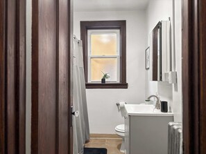 Un baño estrecho con ventana, inodoro y lavamanos.
