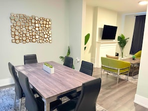 A modern dining area with a wooden table, black chairs, and a decorative wall piece. - Comfortably Appointed & Spacious 3BR Apartment (Chicago)