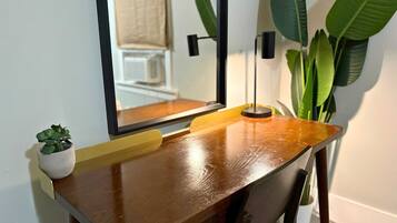 Uma mesa de madeira com um espelho, uma pequena planta em vaso e uma luminária.