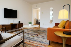 A modern living room with a flat-screen TV, a round coffee table, a sofa, and a patterned rug. - Ideal & Spacious 1BR Apt (Chicago)