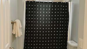 Een badkamer met douchegordijn, toilet, wastafel en handdoekhouder.