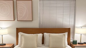 A neatly made bed with two pillows, a folded towel, and a bedside table with a lamp and a green object. - 1BR Chic Apt in Downtown Chicago (Chicago)