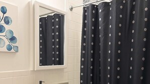A bathroom with a white sink, a mirror, and a black shower curtain with white polka dots. - 1BR Chic Apt in Downtown Chicago (Chicago)