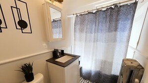 Een kleine badkamer met toilet, wastafel en douchegordijn.